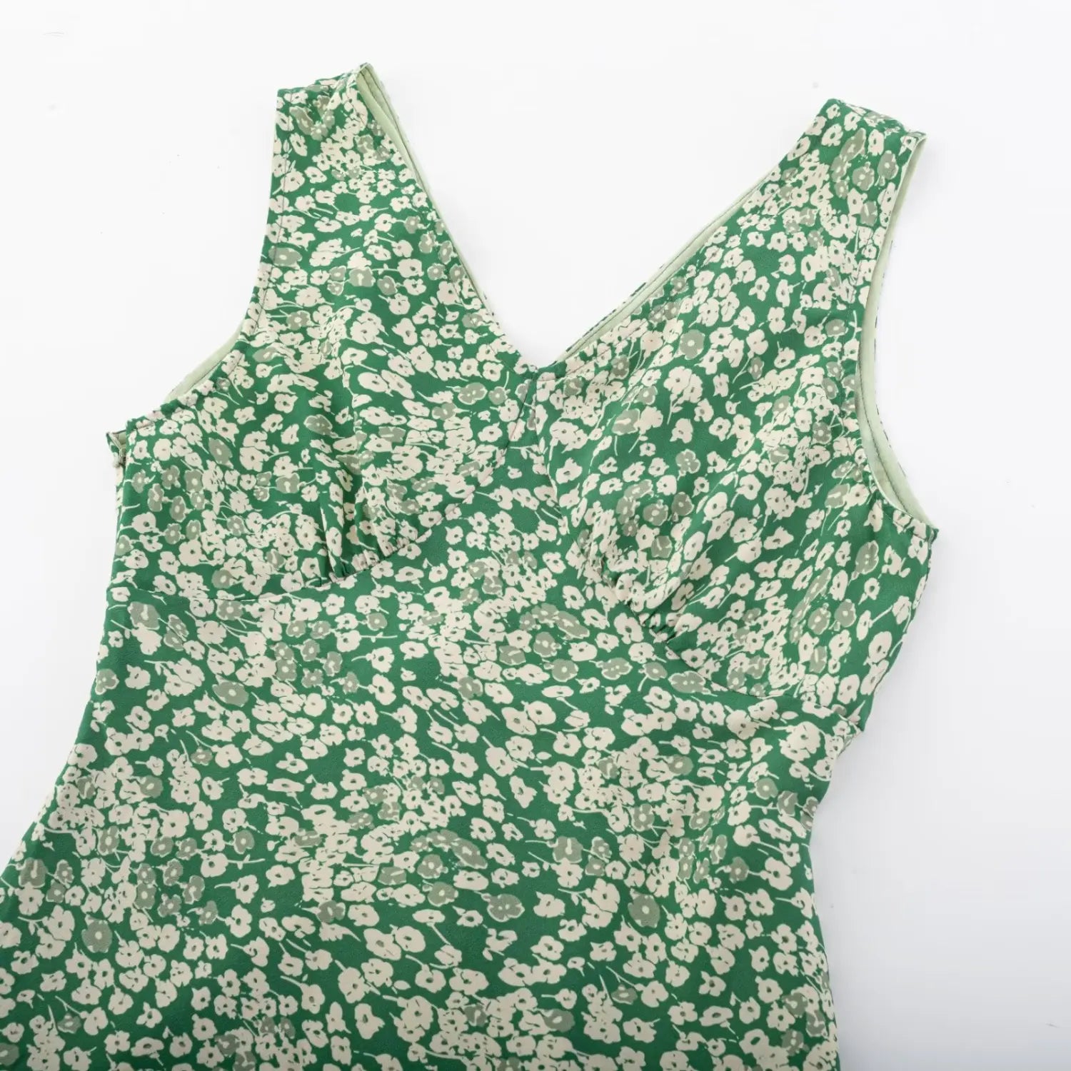 Close-up of V-neck bust part of green floral dress, displaying ruched chest design and all-over floral print