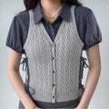 Model wearing grey cable-knit vest over navy gingham shirt with puff sleeves, preppy layered two-piece outfit
