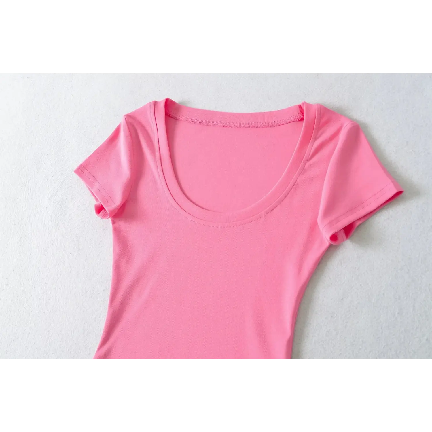 Close-up of U-neck double binding stitching on hot pink ribbed slim short sleeve top