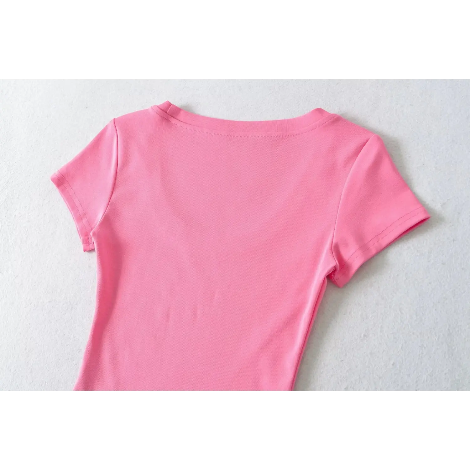 Overhead close shot of hot pink U-neck ribbed tee back torso, smooth stretch fabric and back neck stitching