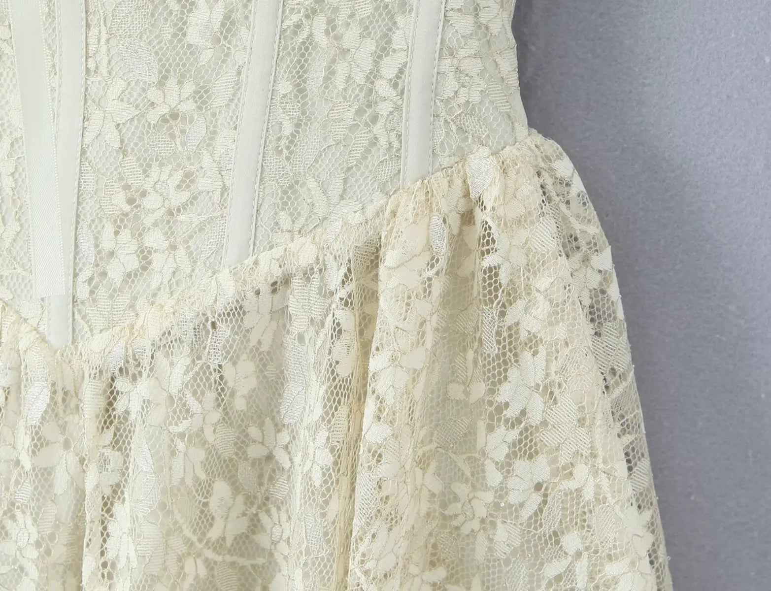 Detailed view of lace fabric and corset-style bodice on ivory mini dress