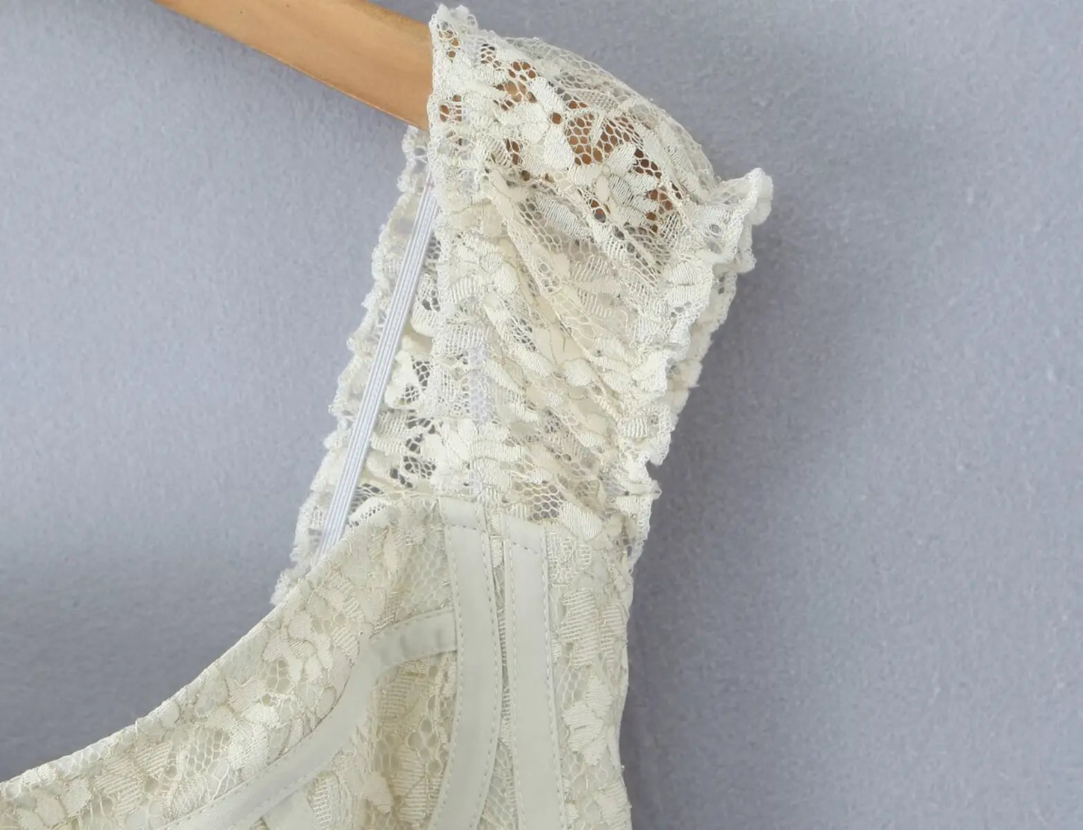 Close-up of lace shoulder straps and square neckline on ivory lace dress