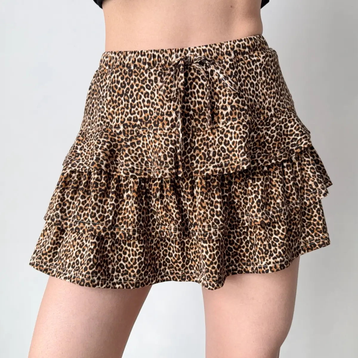 Model wearing leopard print ruffled mini skirt, three-quarter view