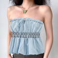 Model wearing light blue smocked bandeau tube top with front tie detail