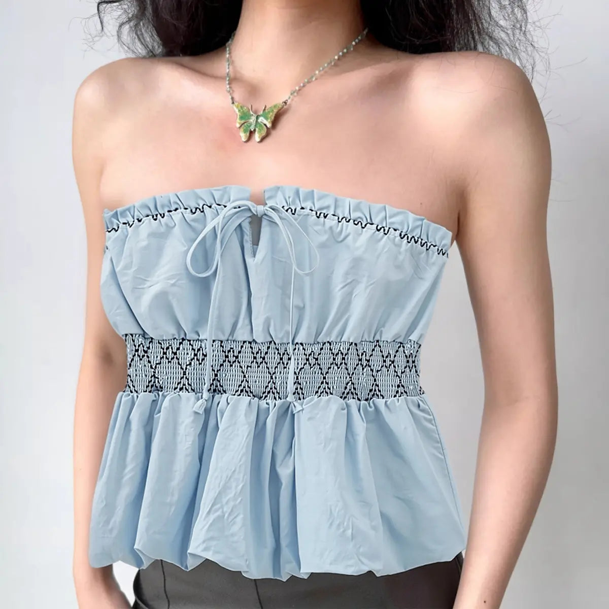 Model wearing light blue smocked bandeau tube top with front tie detail