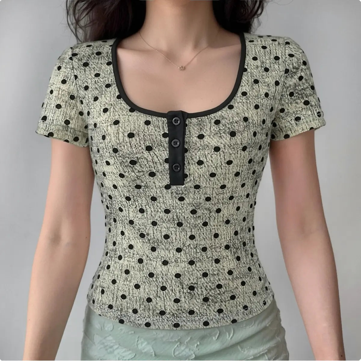 Model wearing light gray polka dot Henley short sleeve top