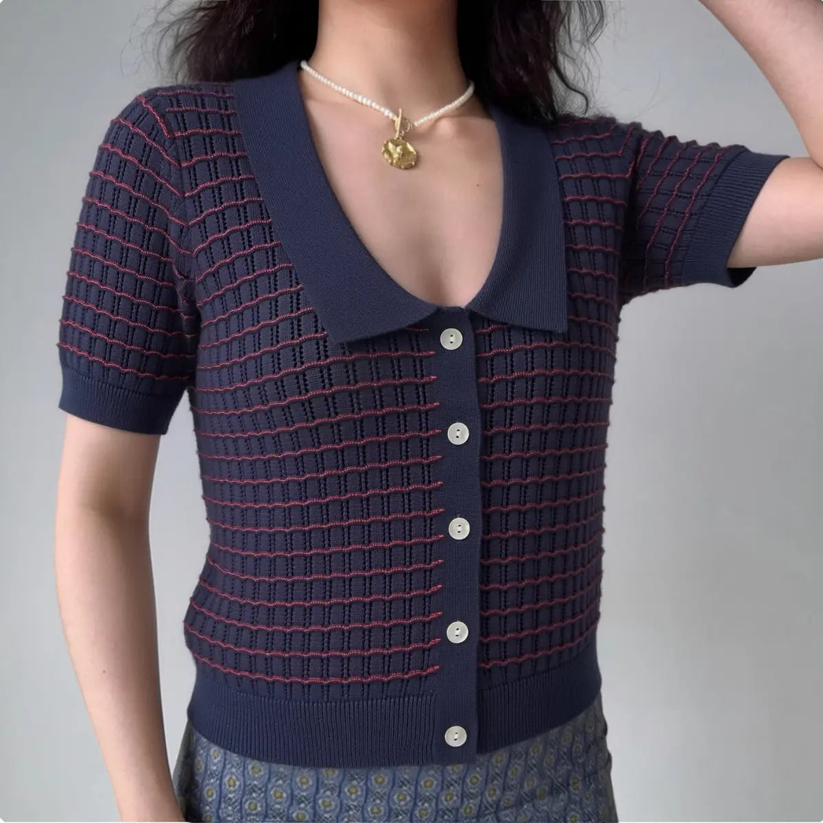 Model wearing navy red stripe knit cardigan with Peter Pan collar and button front, retro-inspired short-sleeve sweater