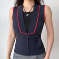 Model wearing navy knit vest with red contrast piping, buckle belt and tailored silhouette