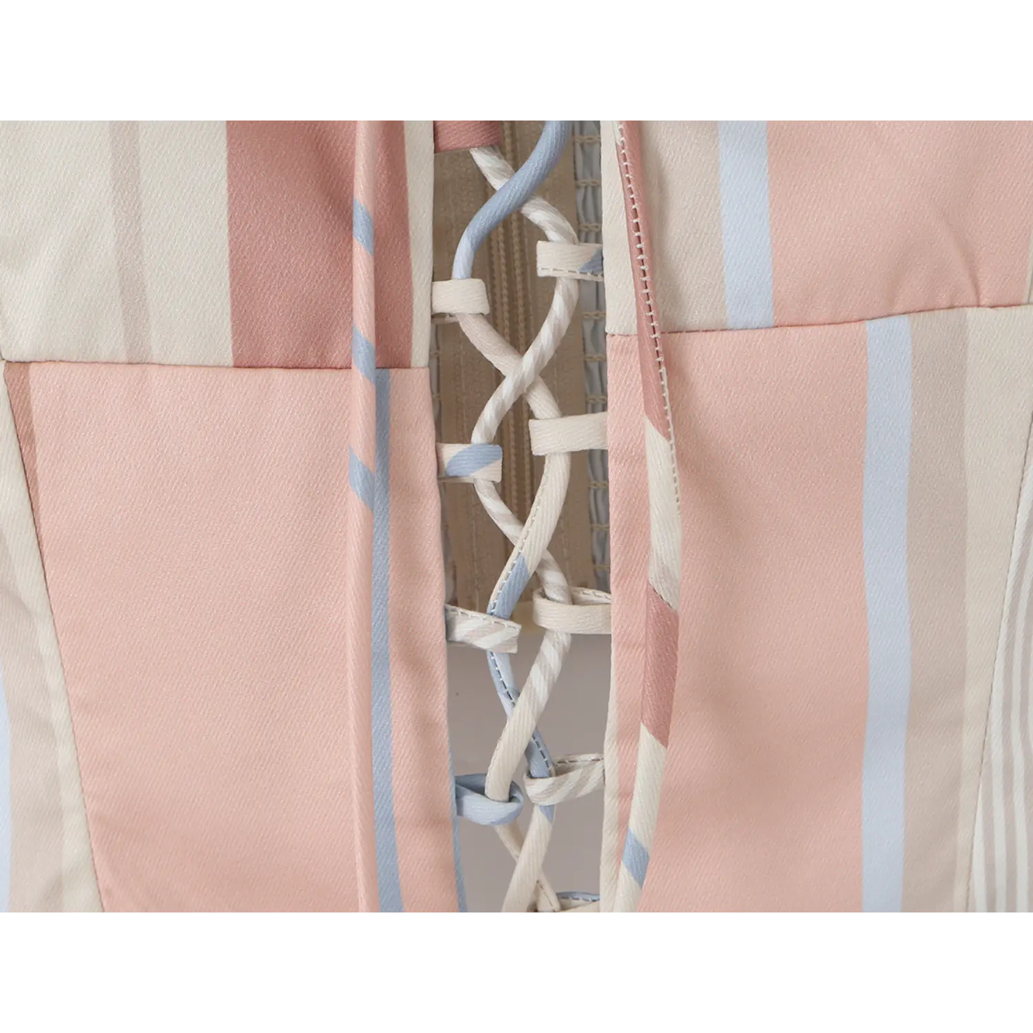 Mid torso lace-up close-up, alternating pink, cream, light blue ribbon crisscross hollow design