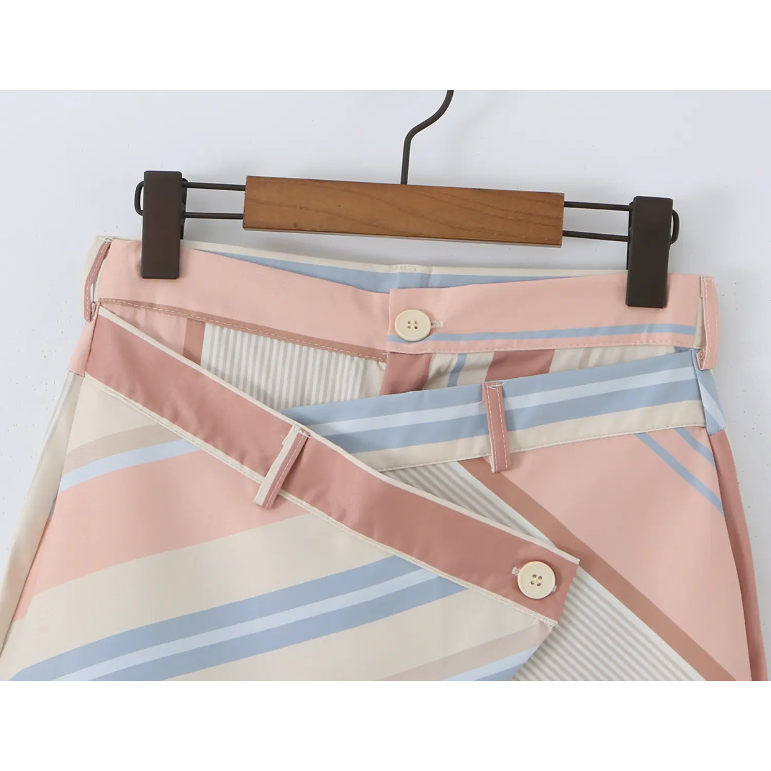 Close-up of double-layer high waistband, inner fly four-hole button, diagonal wrap flap with outer matching cream button and fabric belt loops