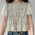 Model wearing off-white gingham blouse with floral embroidery and side drawstrings, vintage-inspired short-sleeve top