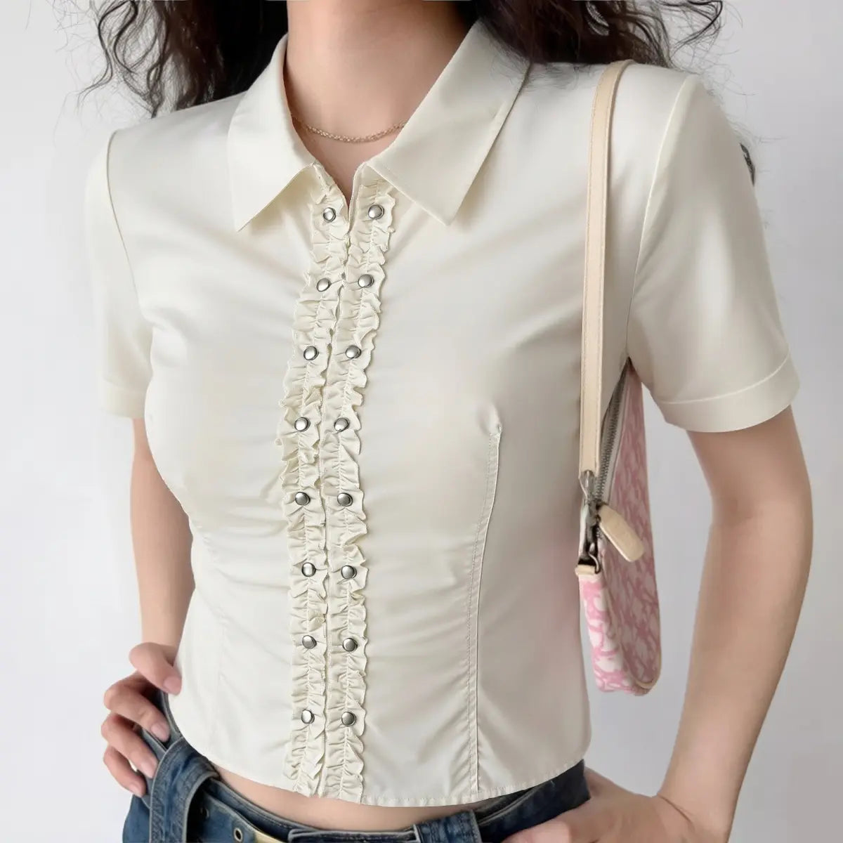 Model wearing off-white short-sleeve blouse with ruffled button placket and Peter Pan collar, preppy cropped shirt