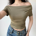 Outfit view of olive green ribbed off-the-shoulder top styled with denim jeans, highlighting the stretchy fabric