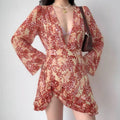 Model wearing orange-red floral chiffon dress with deep V-neck and ruffled hem