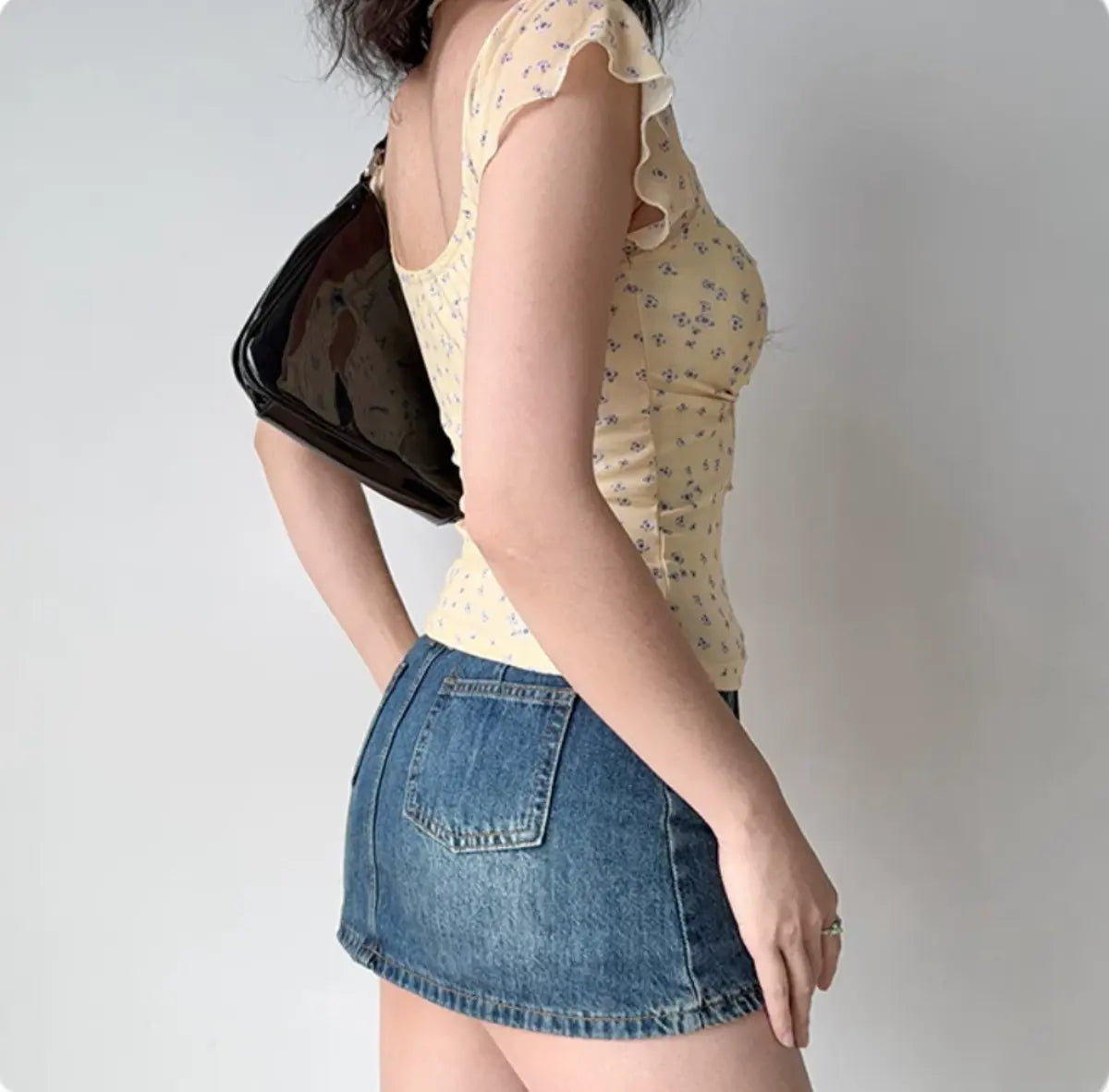 Back view of pale yellow floral mesh top with sheer ruffled sleeves and cropped hem