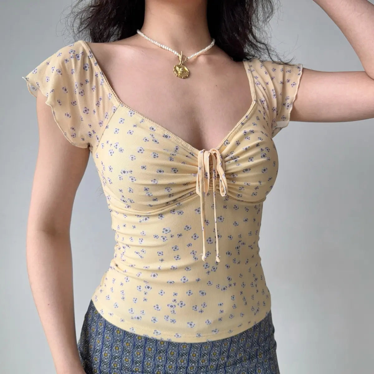 Front view of pale yellow floral mesh top showing the front tie detail and fitted waist
