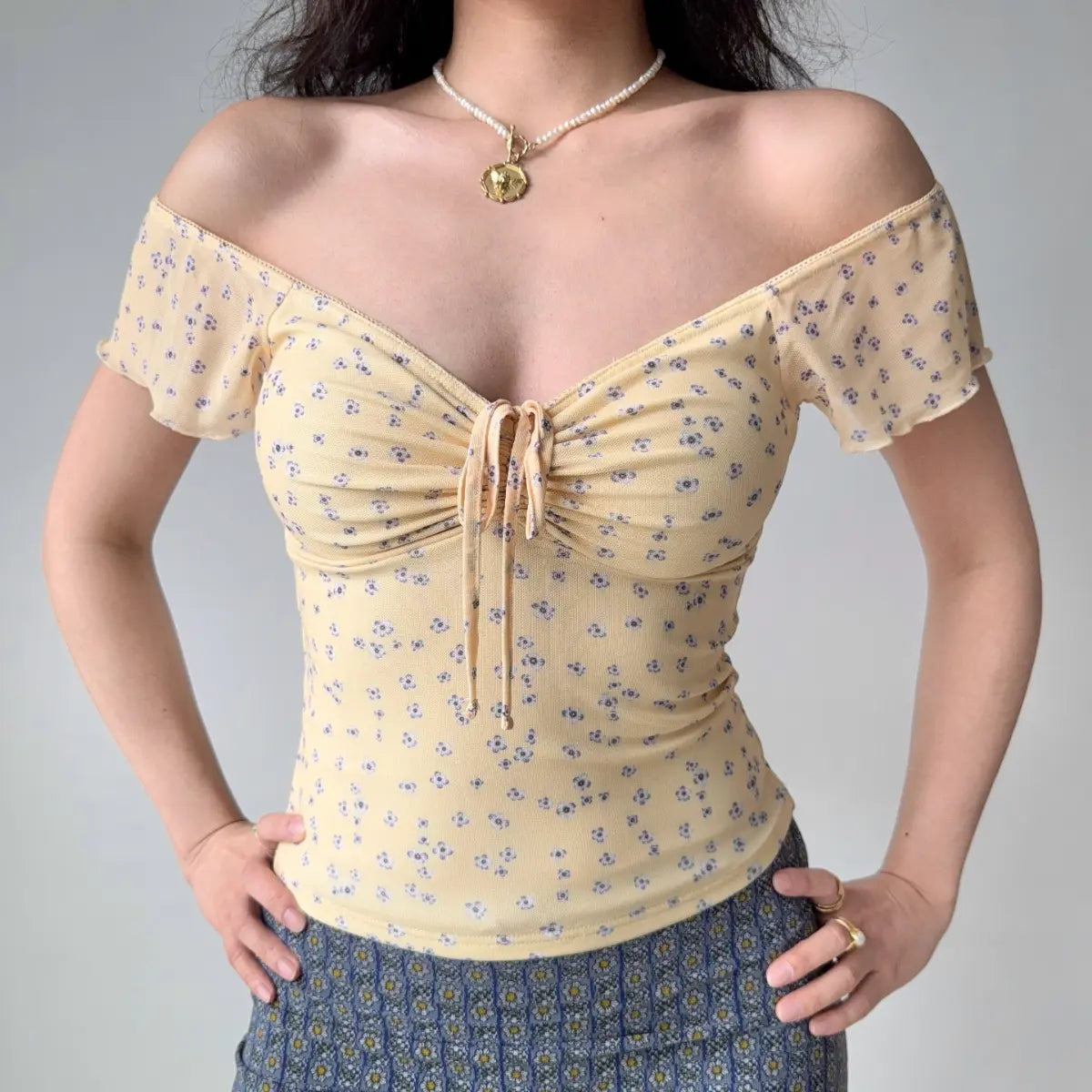 Outfit view of pale yellow floral mesh top styled with denim shorts