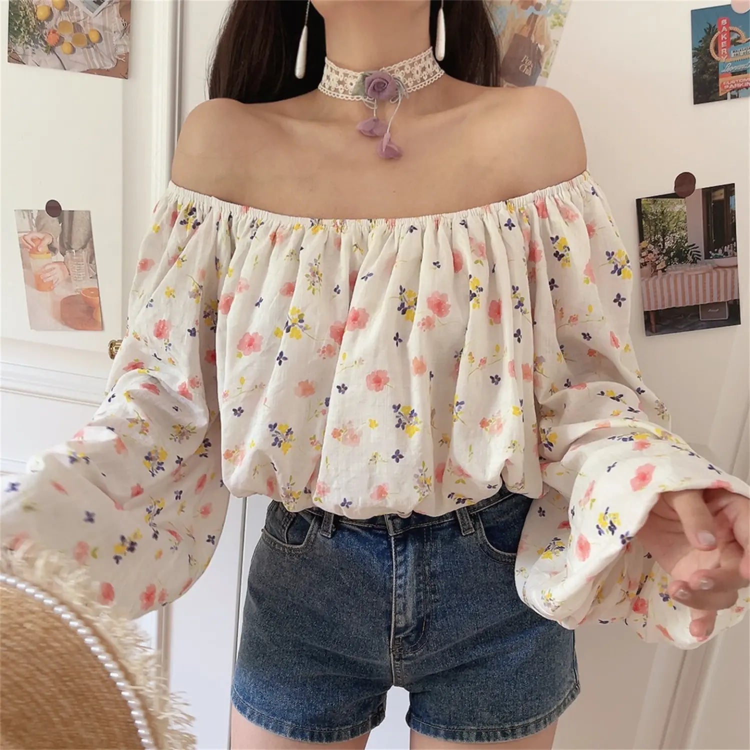 Slightly side front shot of white floral off shoulder blouse, loose bubble sleeves, cropped hem match denim shorts