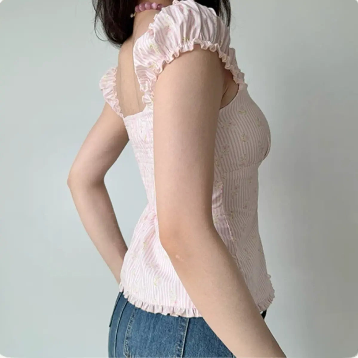 Side view of pink floral gingham top with fitted corset-style silhouette and ruffled cap sleeves