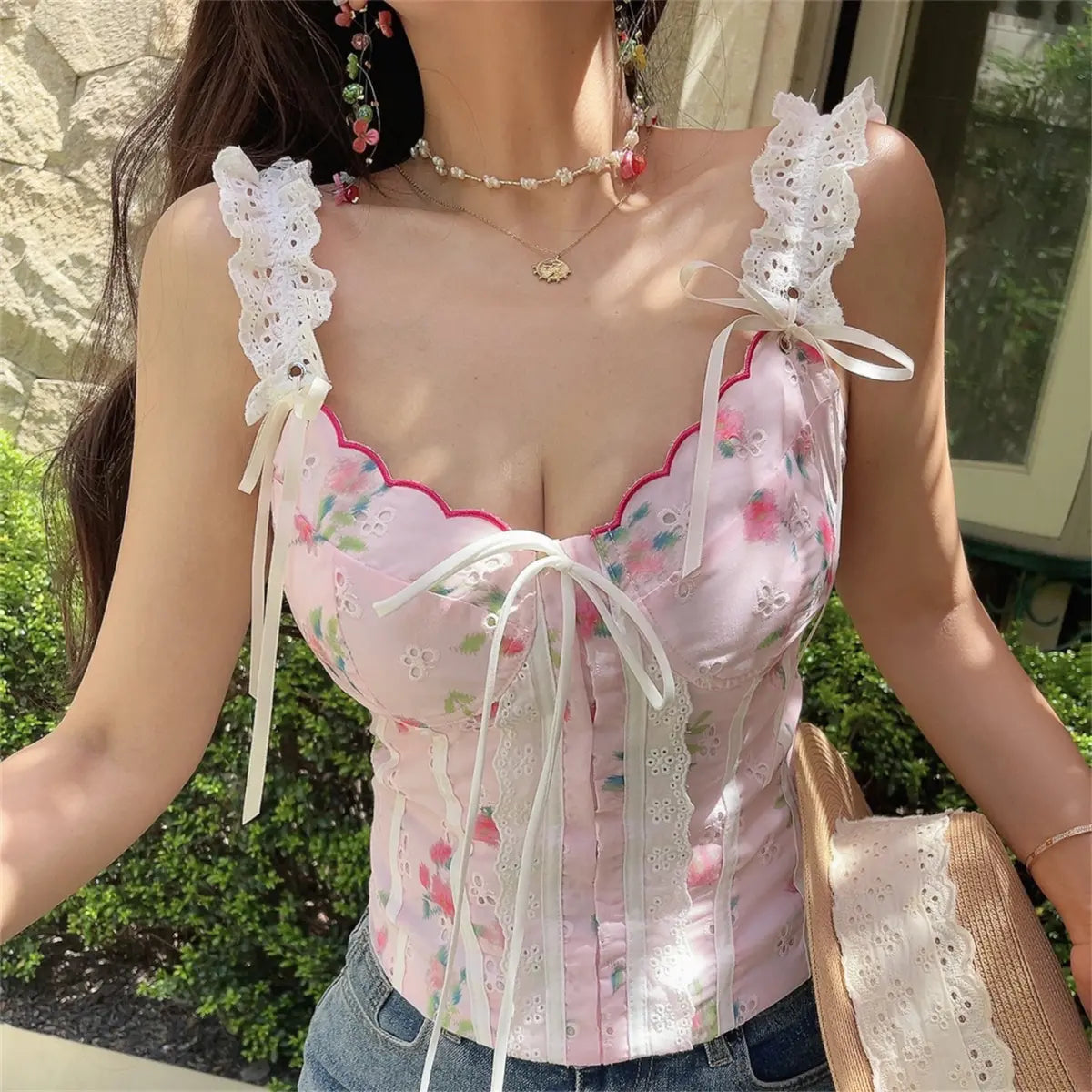 Front view of pink floral lace camisole top on model