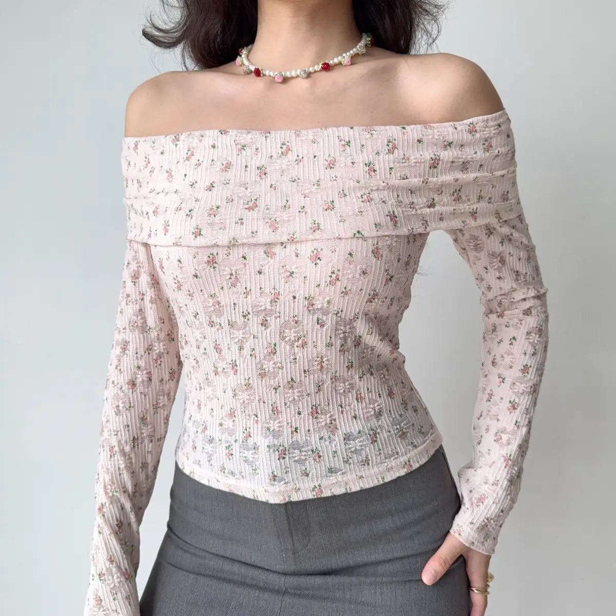 Model wearing pink floral-print off-the-shoulder top with ribbed texture and sheer lace detail, fitted long-sleeve blouse