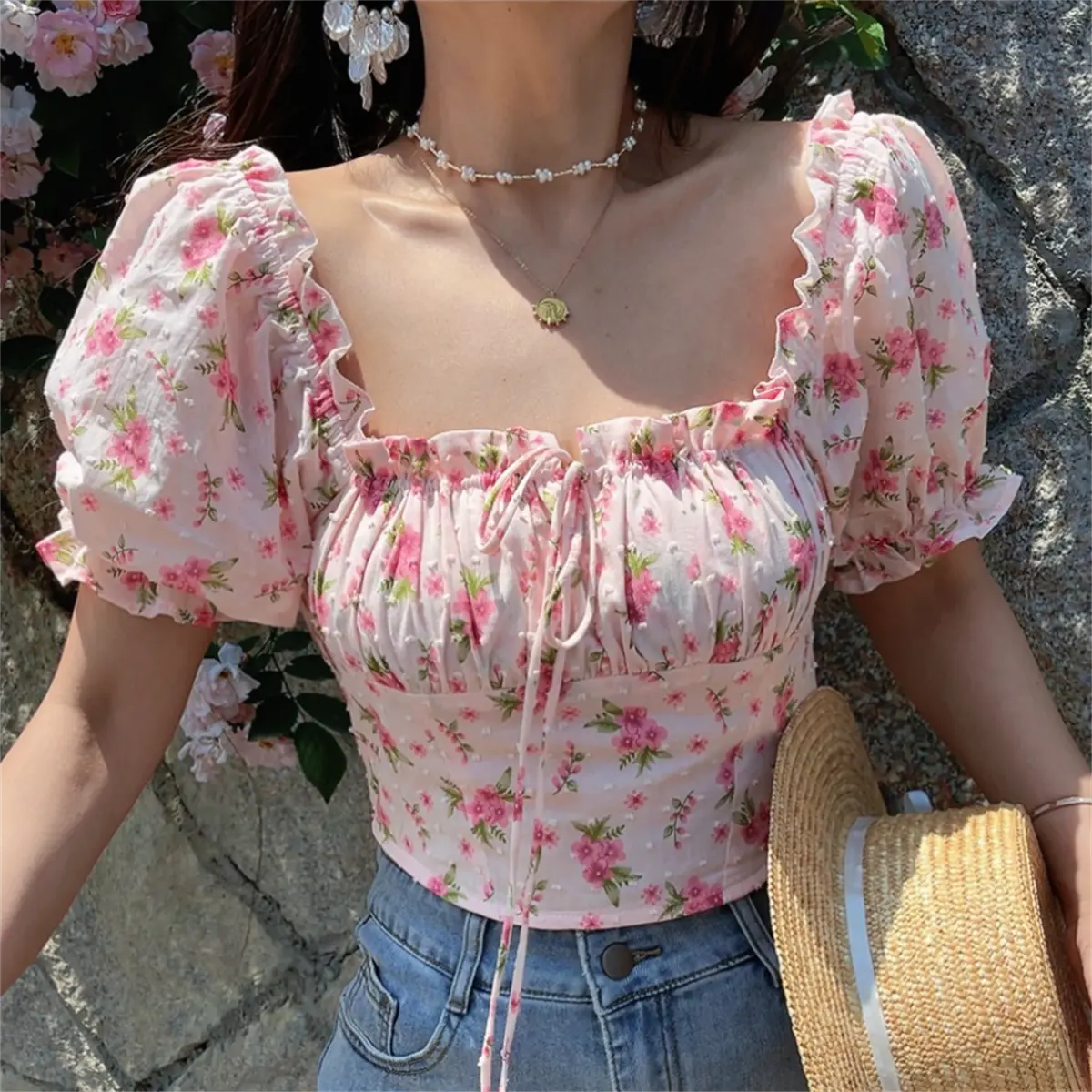 Model wearing pink floral print square-neck cropped top with puff sleeves, ruffled trim, and front drawstring tie