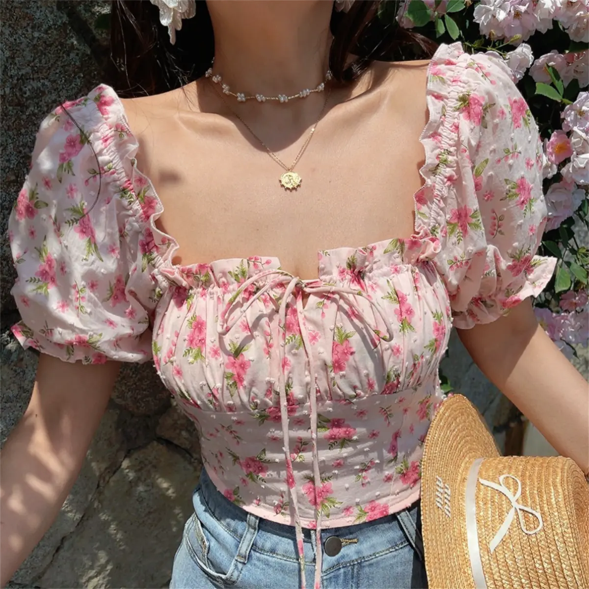 Front view of pink floral print top showing the square neckline, puff sleeves, and front drawstring tie detail