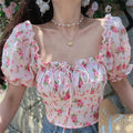 Outfit view of pink floral print top styled with denim shorts, highlighting the fitted cropped silhouette