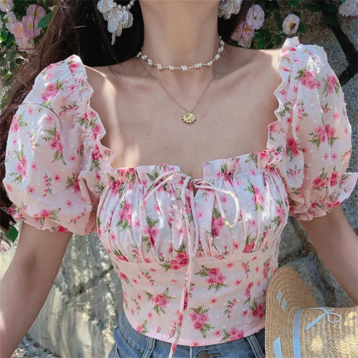 Outfit view of pink floral print top styled with denim shorts, highlighting the fitted cropped silhouette