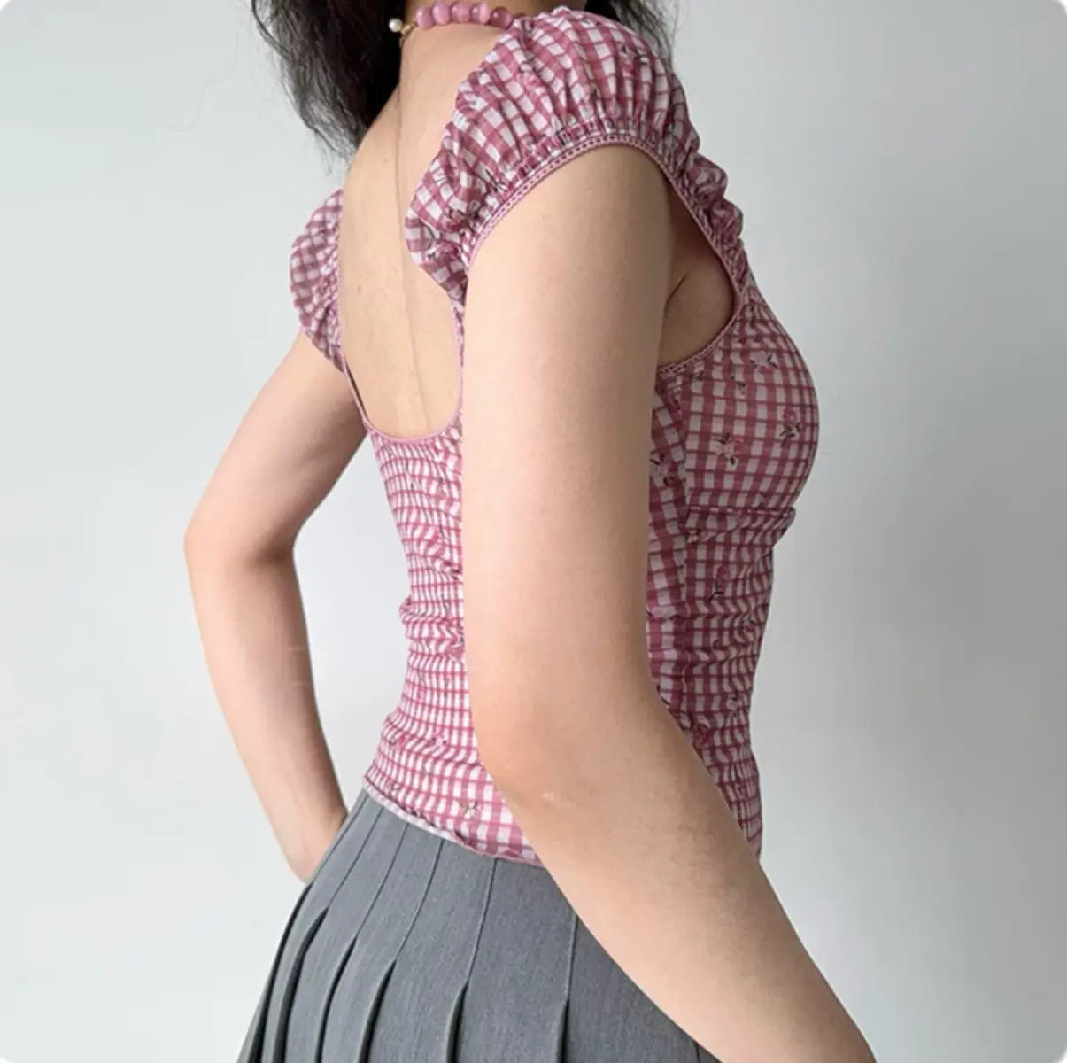Back view of pink gingham corset-style top with puff sleeves and open-back design