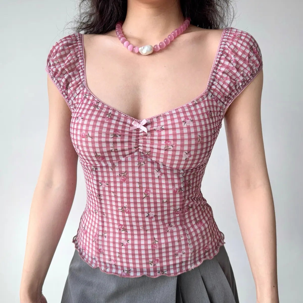 Front view of pink gingham top with square sweetheart neckline, puff sleeves and delicate bow detail