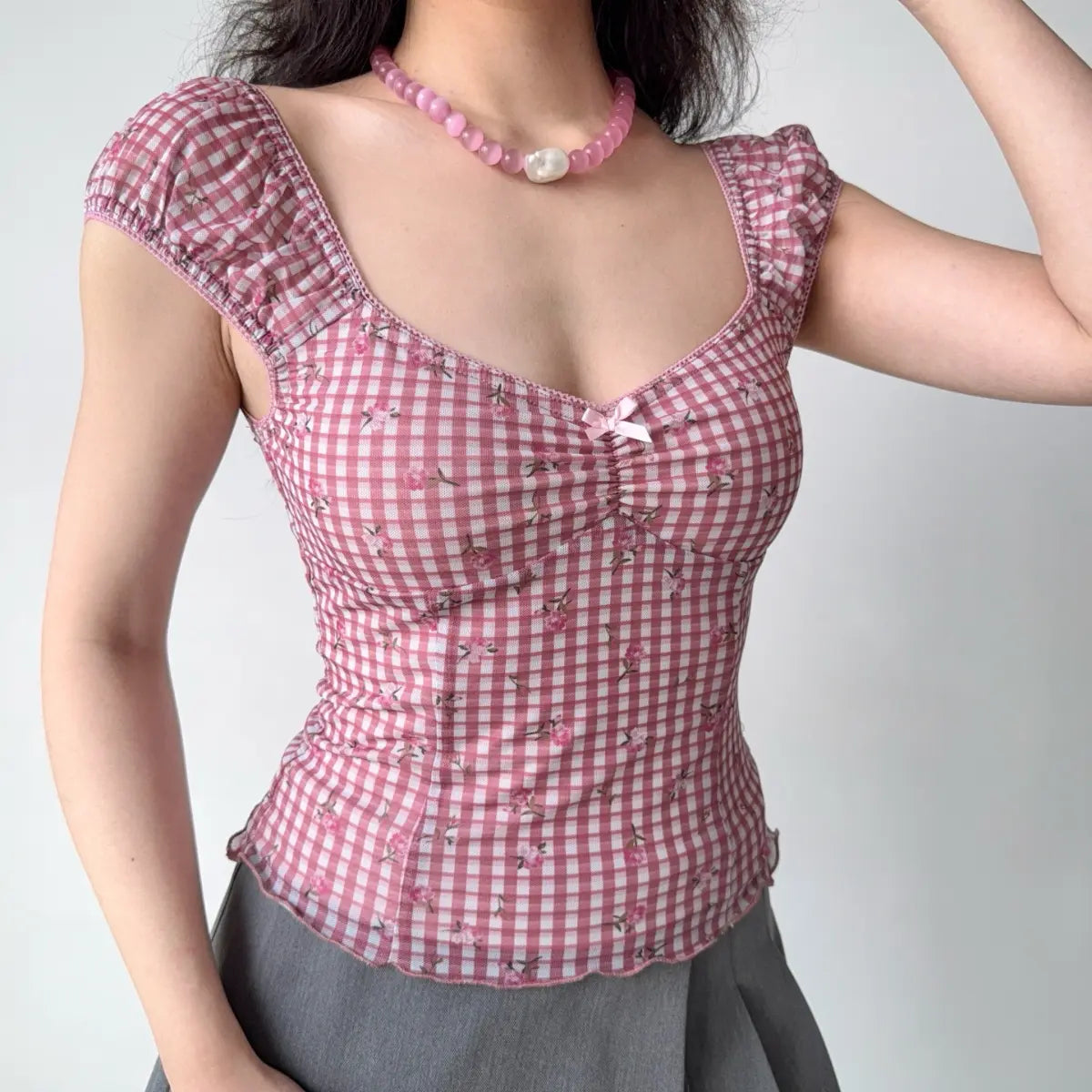 Outfit view of pink gingham corset-style top showing the fitted waist and floral embroidery