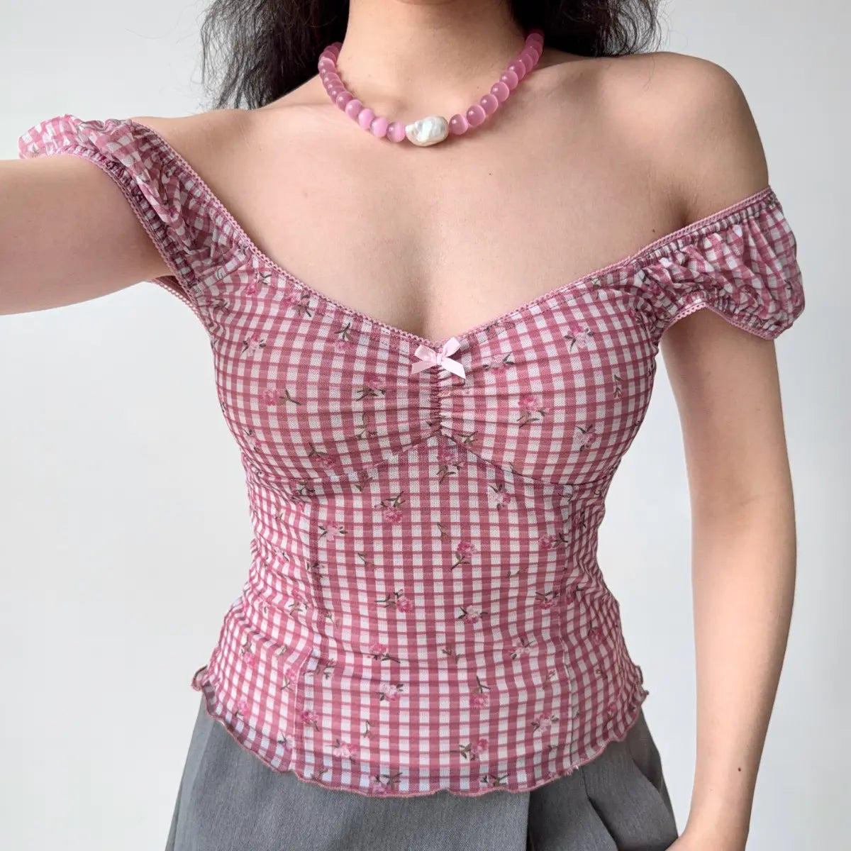 Model wearing pink gingham off-the-shoulder corset-style top with sweetheart neckline, puff sleeves and fitted boned silhouette