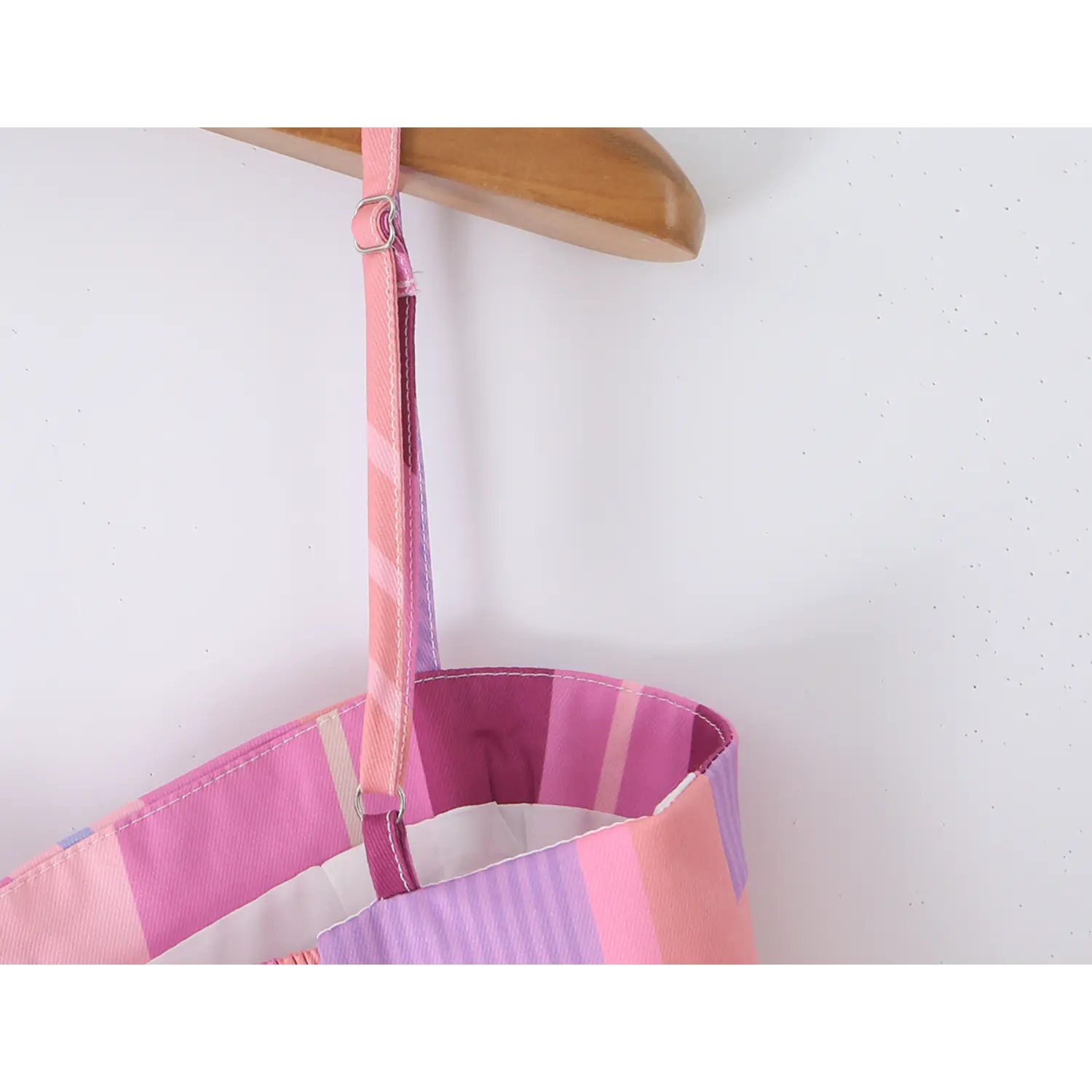 Inner close-up of striped spaghetti strap with silver metal slider adjuster, clean inner lining stitching