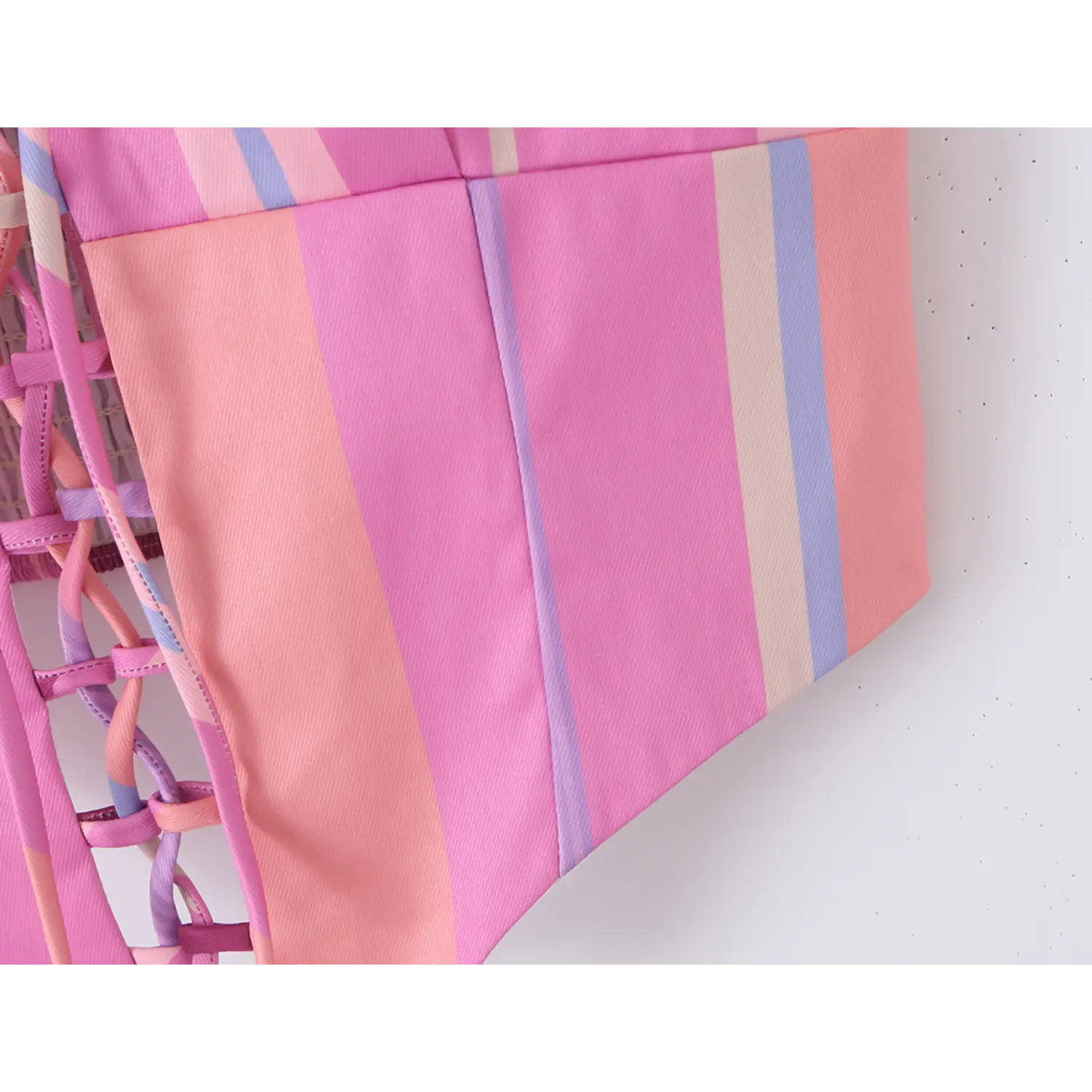 Close-up of curved pointed hem and vertical bust panel stitching on pastel striped corset cami, smooth woven fabric texture