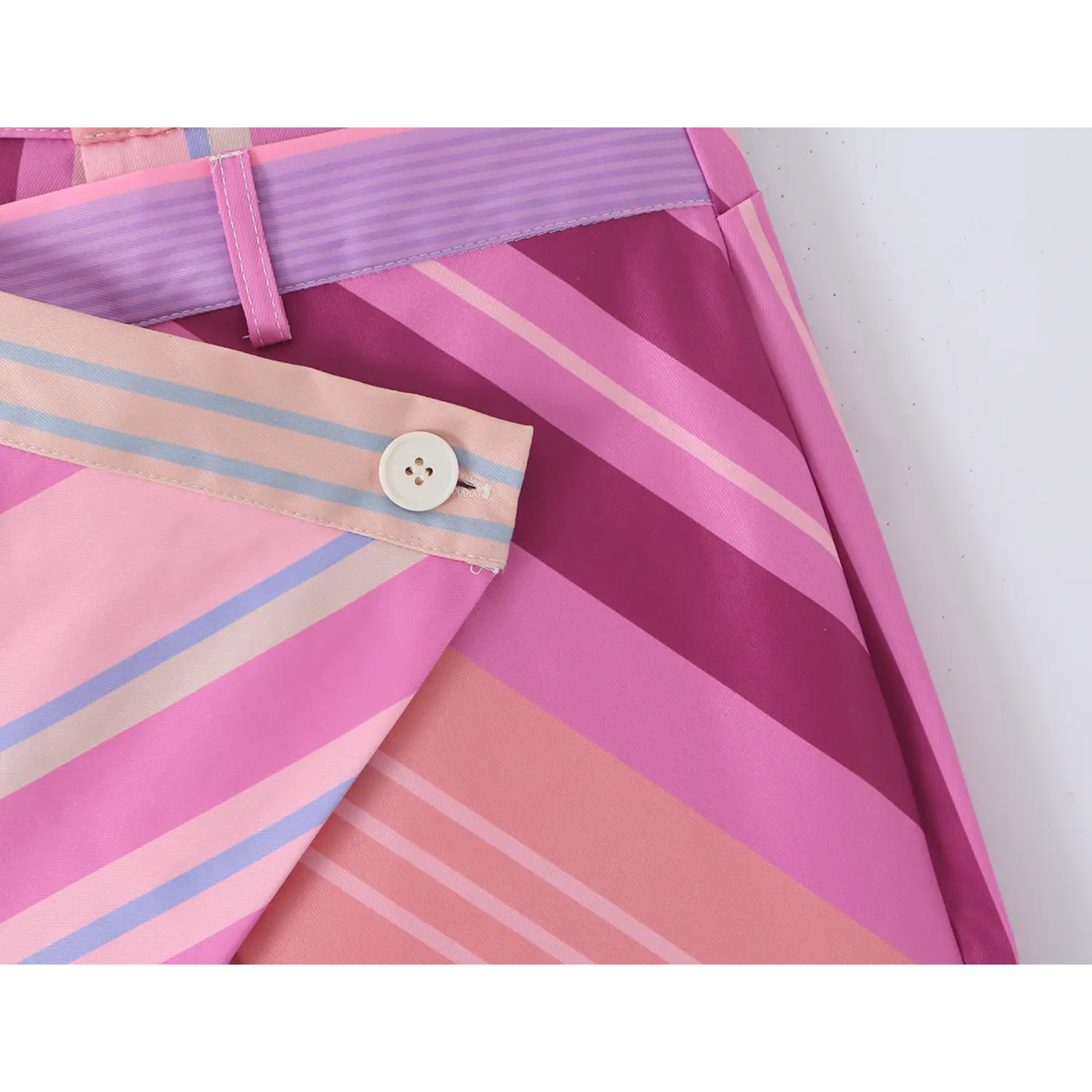 Macro shot of off-white four-hole button sewn on diagonal striped wrap overlay, neat edge topstitching