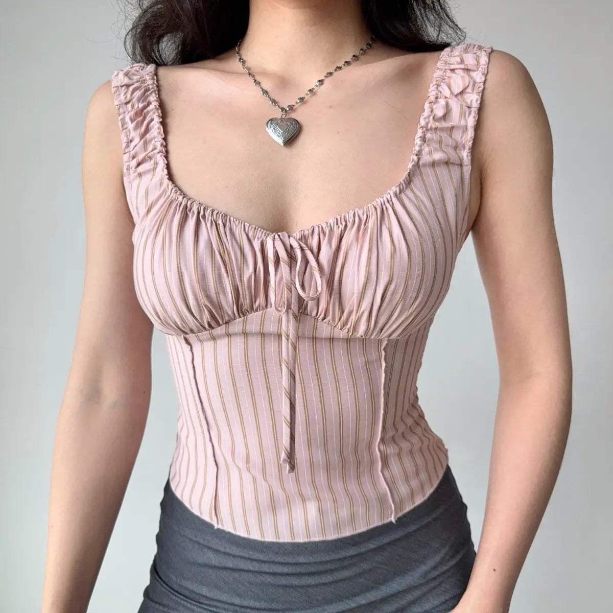 Model wearing pink striped corset-style cami top with ruched sweetheart neckline, ruffled straps and fitted boned silhouette