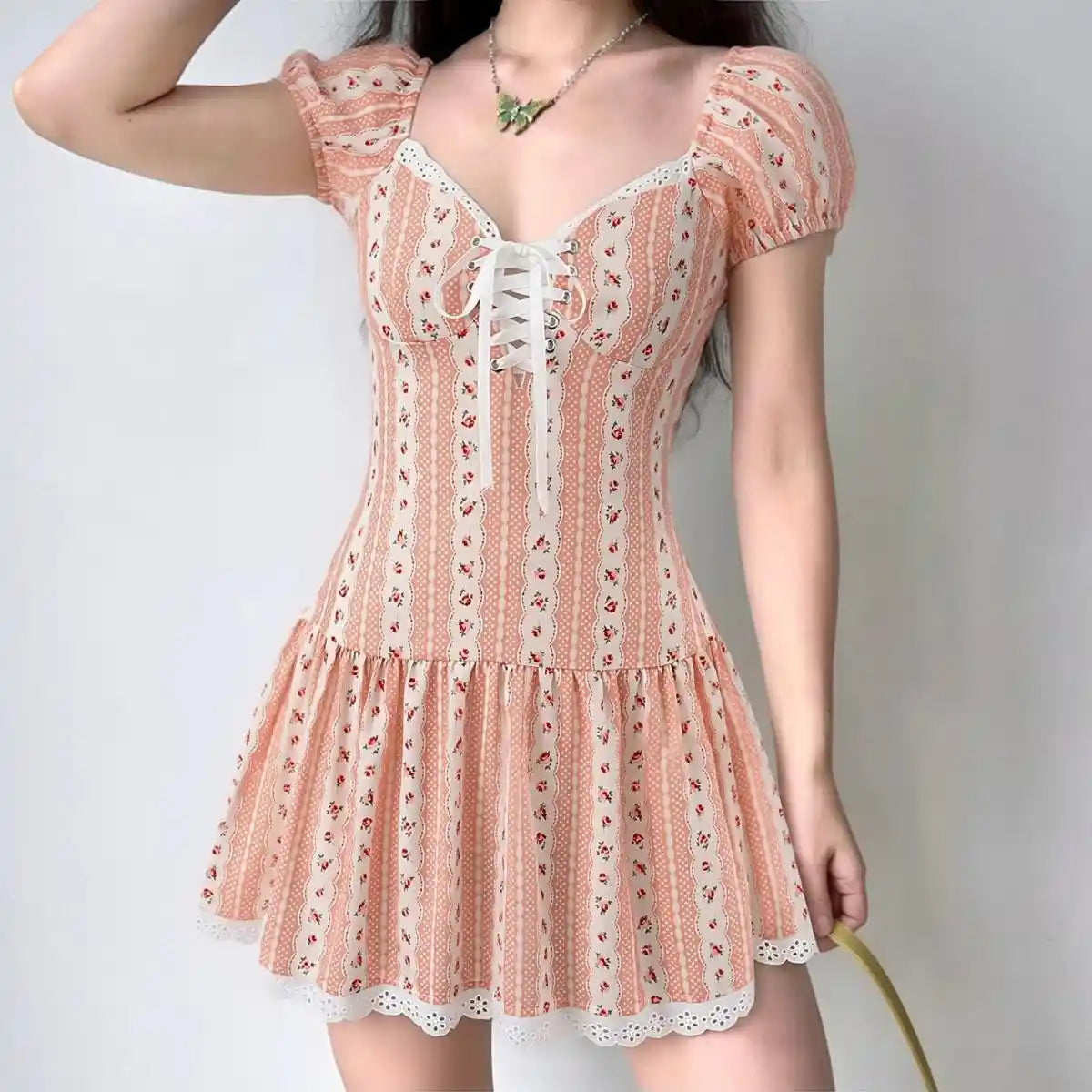 Model wearing pink white ditsy floral puff-sleeve corset mini dress with lace-up front, feminine cottagecore outfit