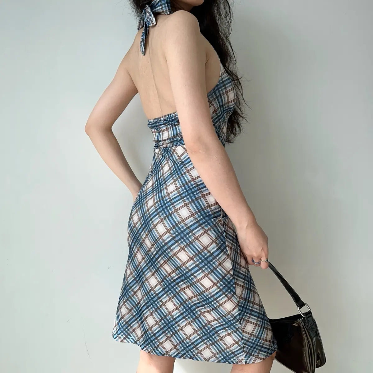 Back view of plaid halter dress with open-back design and halter neckline
