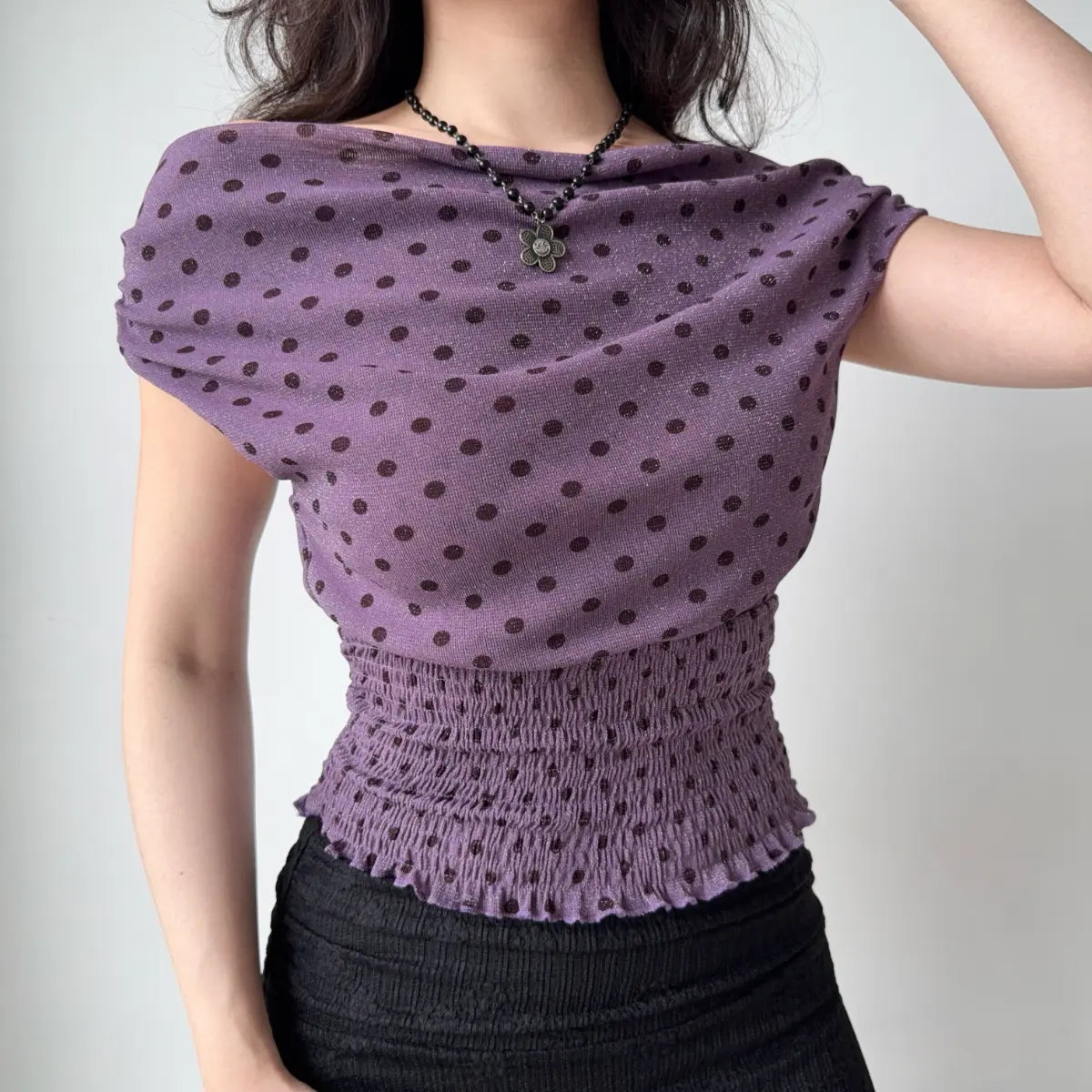 Model wearing purple polka-dot off-the-shoulder top, posing to show side fit and fabric sheen