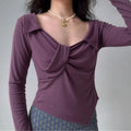 Model wearing purple long-sleeve top with twist-front detail and square neckline, form-fitting knit blouse