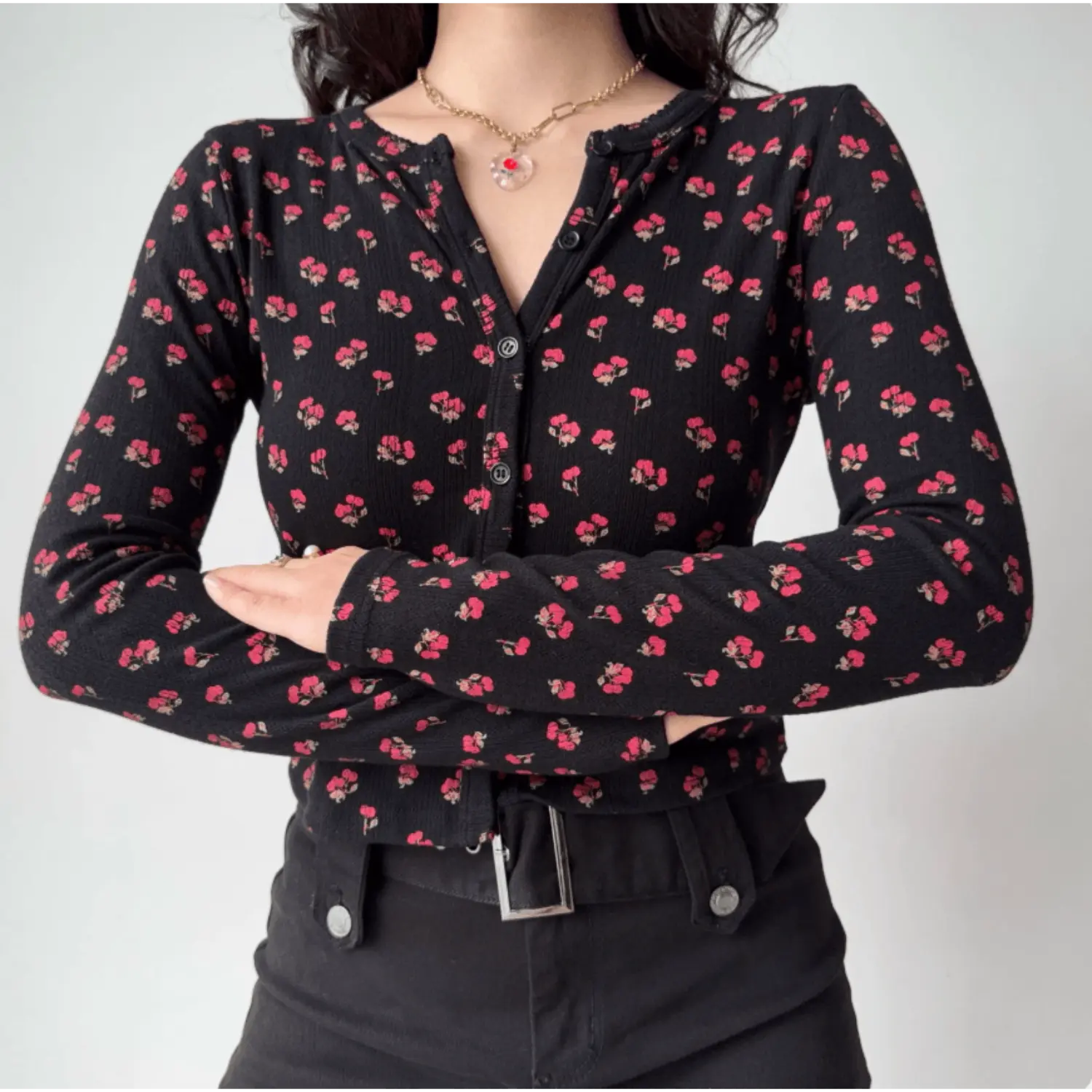 Model cross‑arm pose wearing black ditsy red floral print long sleeve button top