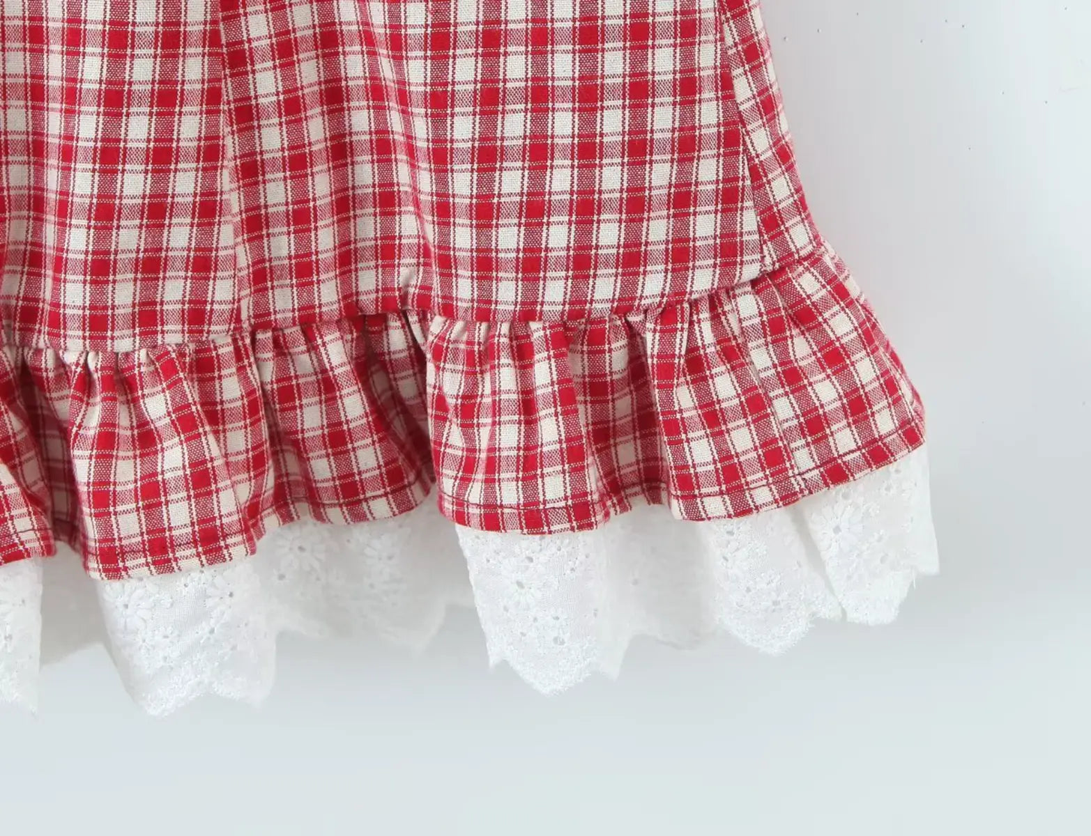 Ruffled hem and lace trim detail of red gingham halter dress