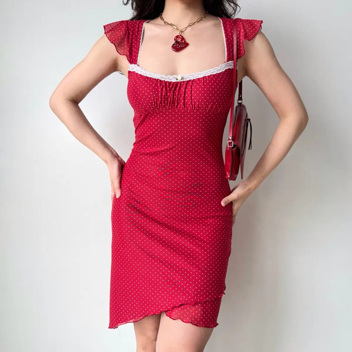 Outfit view of red polka dot dress styled with accessories, showing the layered mesh hem detail