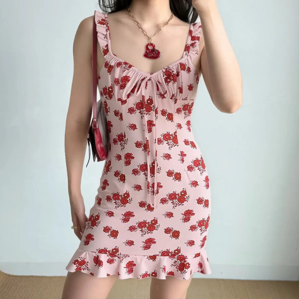 Model wearing pink rose print mini dress with ruffled straps and bodycon fit