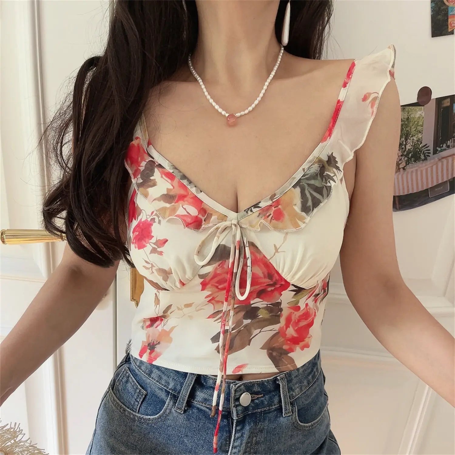 Slightly side front shot of ruffle strap floral cami, adjustable shoulder strap, cropped hem waist detail