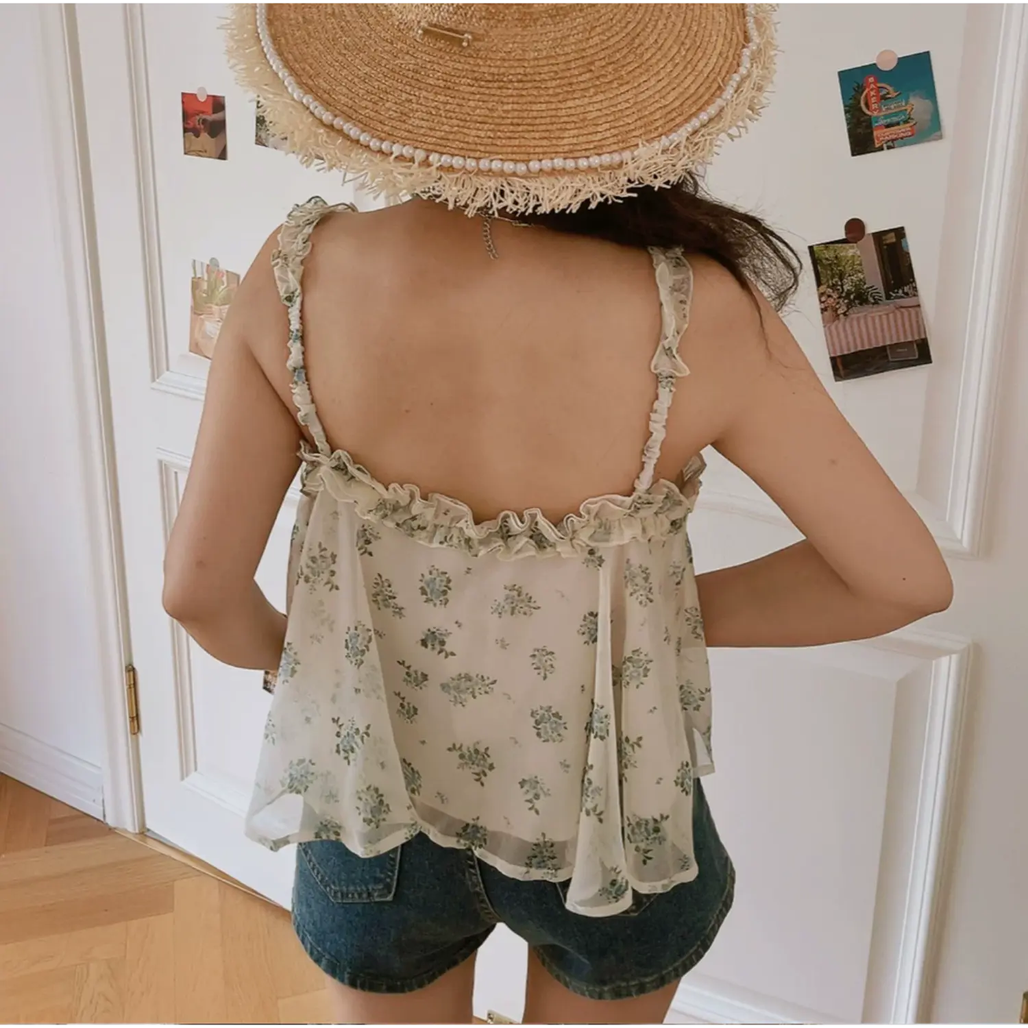 Back lifestyle shot of cream base blue small floral ruffle strap cami top, full low open back, elastic frill shoulder straps, flowy loose swing hem