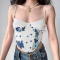 Model wearing white and blue floral corset cami top with thin straps, styled with jeans