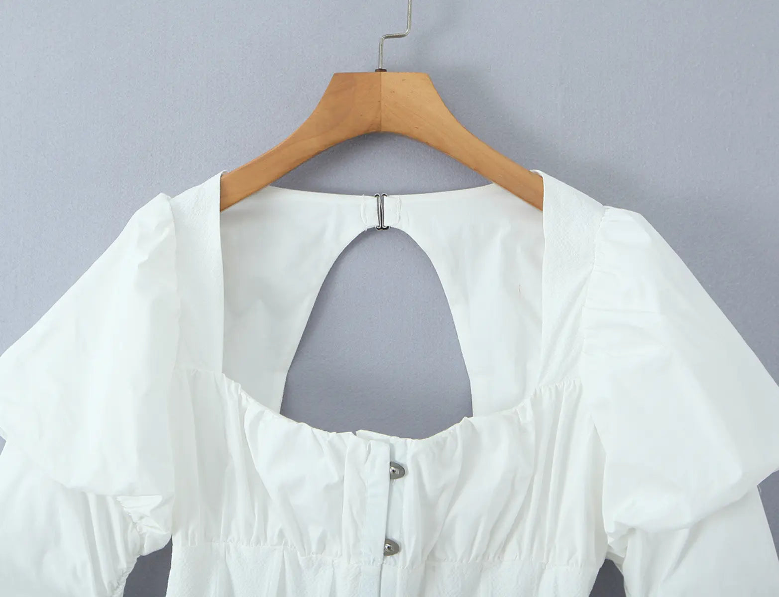 Close-up of square neckline and button placket on white bustier