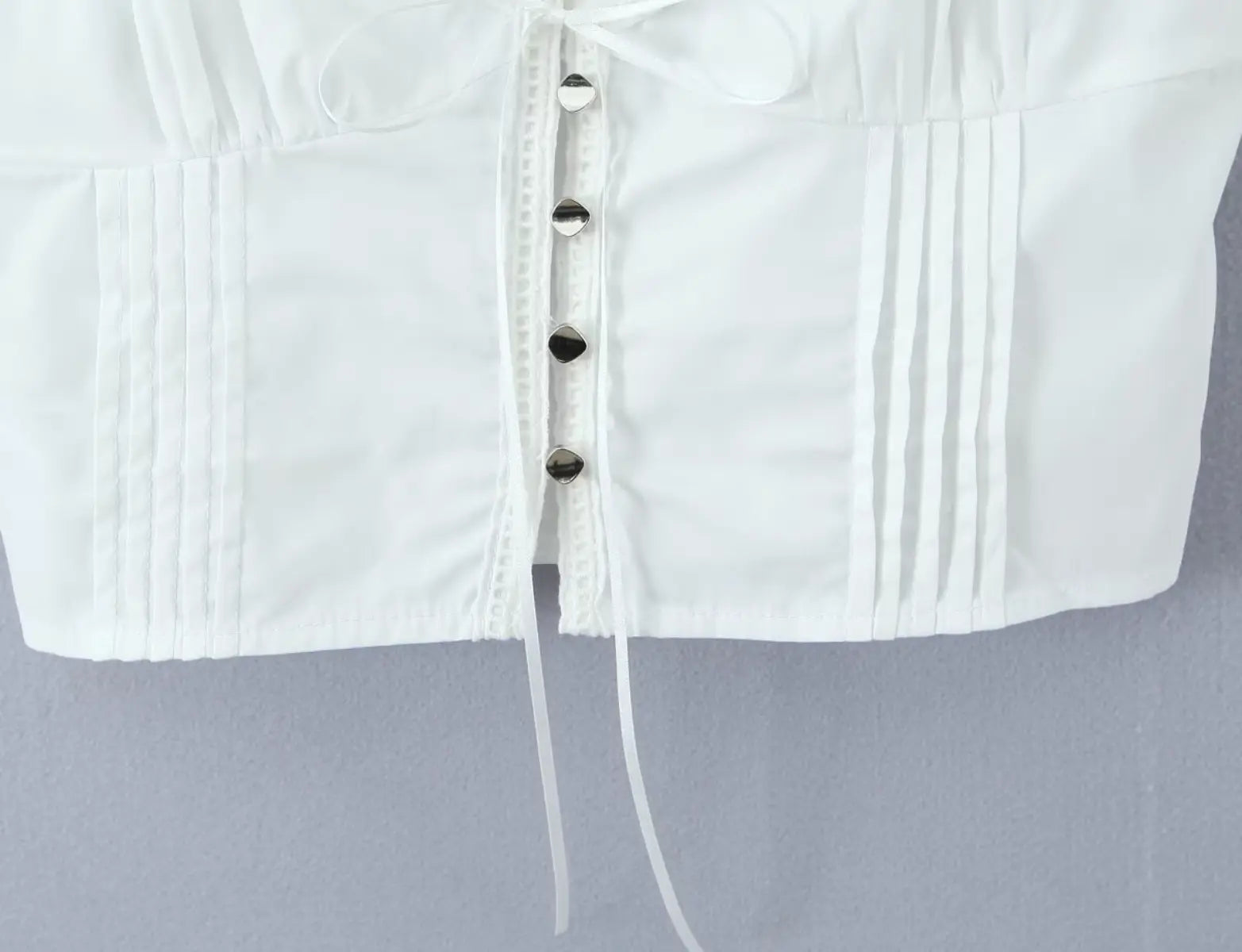 Close-up of button placket and front tie detail on white corset top